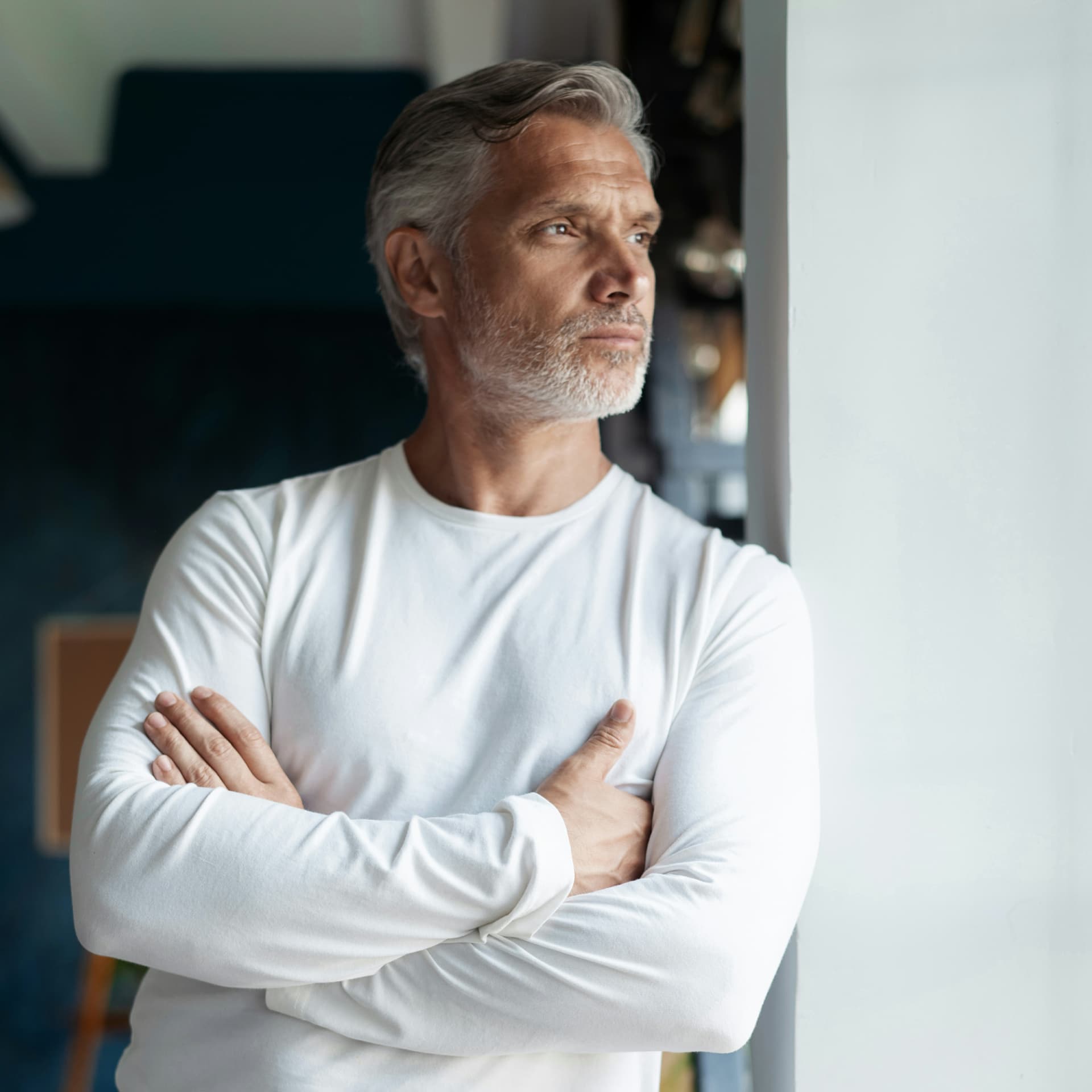 Gray-haired man in a white shirt standing with his arms crossed